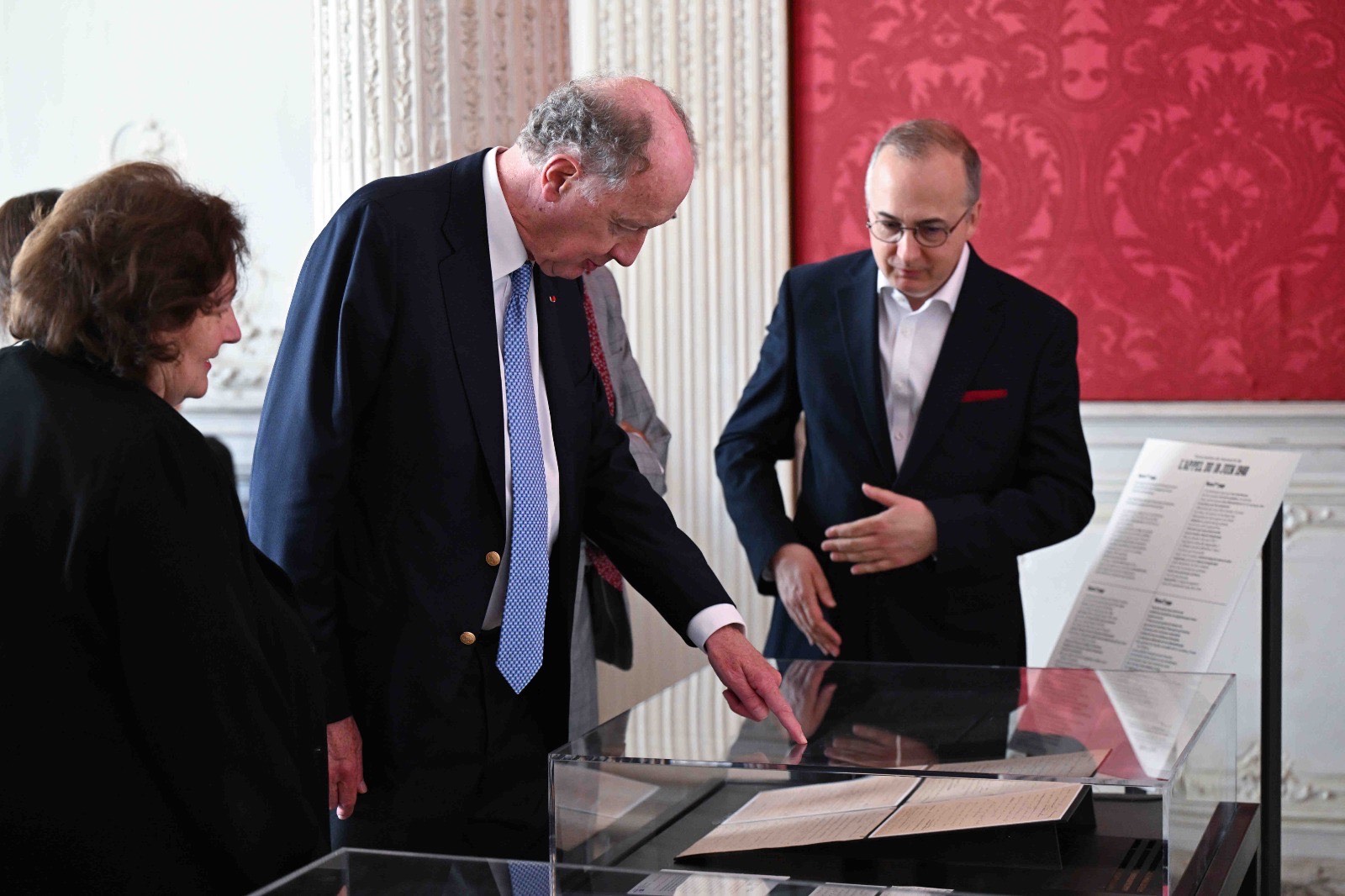 ves de Gaulle regarde le manuscrit, dans une vitrine, en compagnie des commissaires des Archives nationales. 