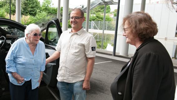 Line Renaud à PSS Line Renaud en chemisier bleu et lunettes de soleil sort de la voiture avec son assistant.