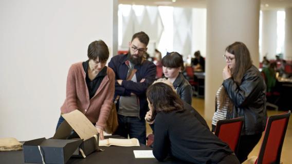 Etudiants autour d'un archiviste dans la salle de lecture Etudiants autour d'un archiviste dans la salle de lecture