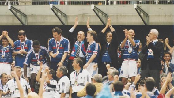 Célébration de la victoire de la coupe du monde de football le 12 juillet 1998, avec des membres de l'équipe, le président de la République Jacques Chirac et le Premier ministre Lionel Jospin Archives nationales, cote 20050145/12 Photographie en couleur de la célébration de la victoire de la coupe du monde de football le 12 juillet 1998, avec des membres de l'équipe en tenue de l'équipe de France, le président de la République Jacques Chirac et le Premier ministre Lionel Jospin.