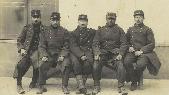 Groupe de poilus assis Archives nationales, cote 700 AP/3, PA 78 (Grand collecte 1914-1918) Photographie en noir et blanc d’un groupe de cinq soldats en uniforme assis sur un banc (Première Guerre mondiale)