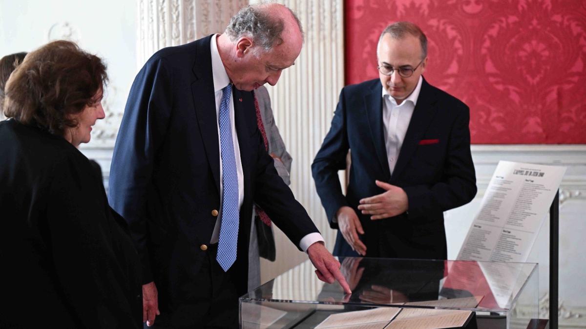 ves de Gaulle regarde le manuscrit, dans une vitrine, en compagnie des commissaires des Archives nationales. 