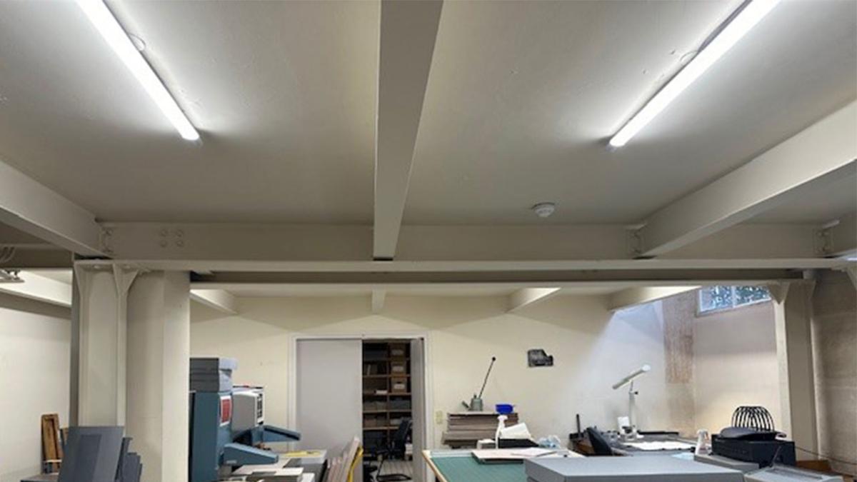 Vue d'un atelier aux murs blancs, avec son éclairage Led au plafond.