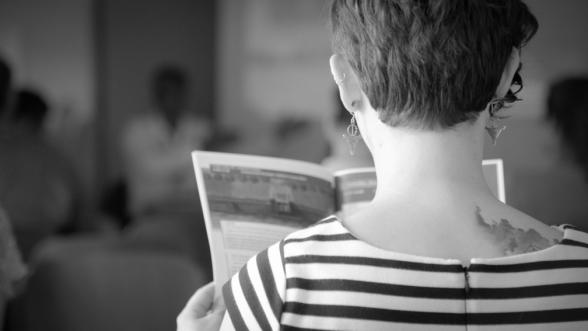 Vue de dos d'une étudiante lisant un programme de conférence