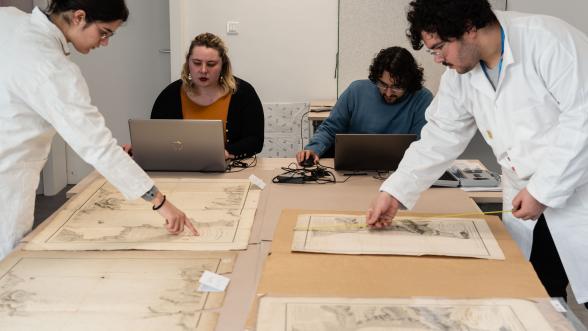 Photographie d'étudiants en cours de travail pour reconitionner des cartes et plans disposés sur une table