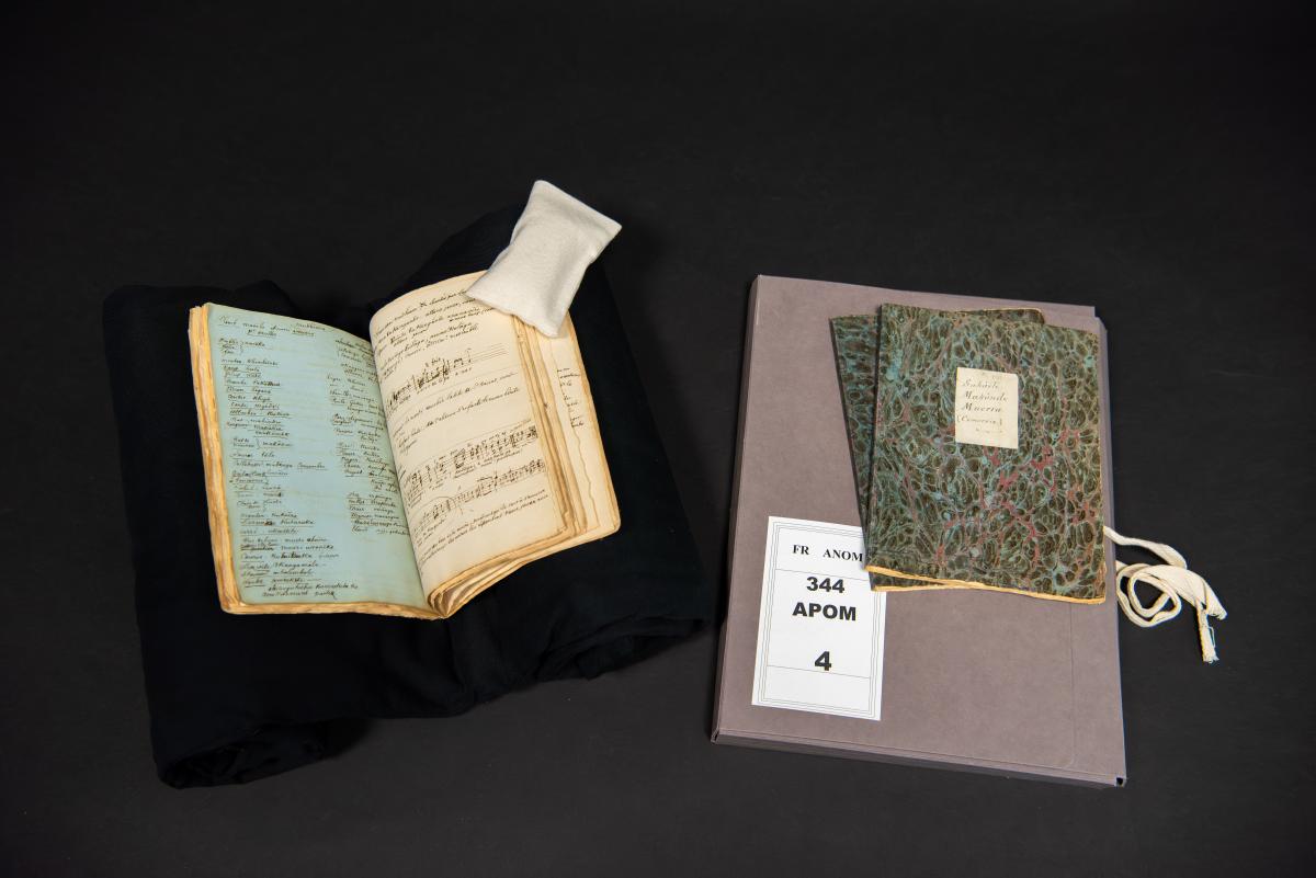 Photographie représentant des documents d'archives posés sur un lutrin et une boite d'archives
