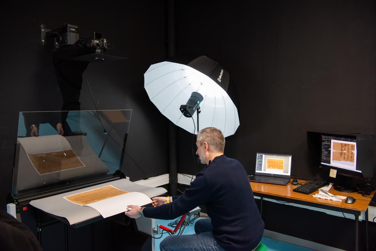 Photographie représentant le photographe des ANOM en train de numériser un folio