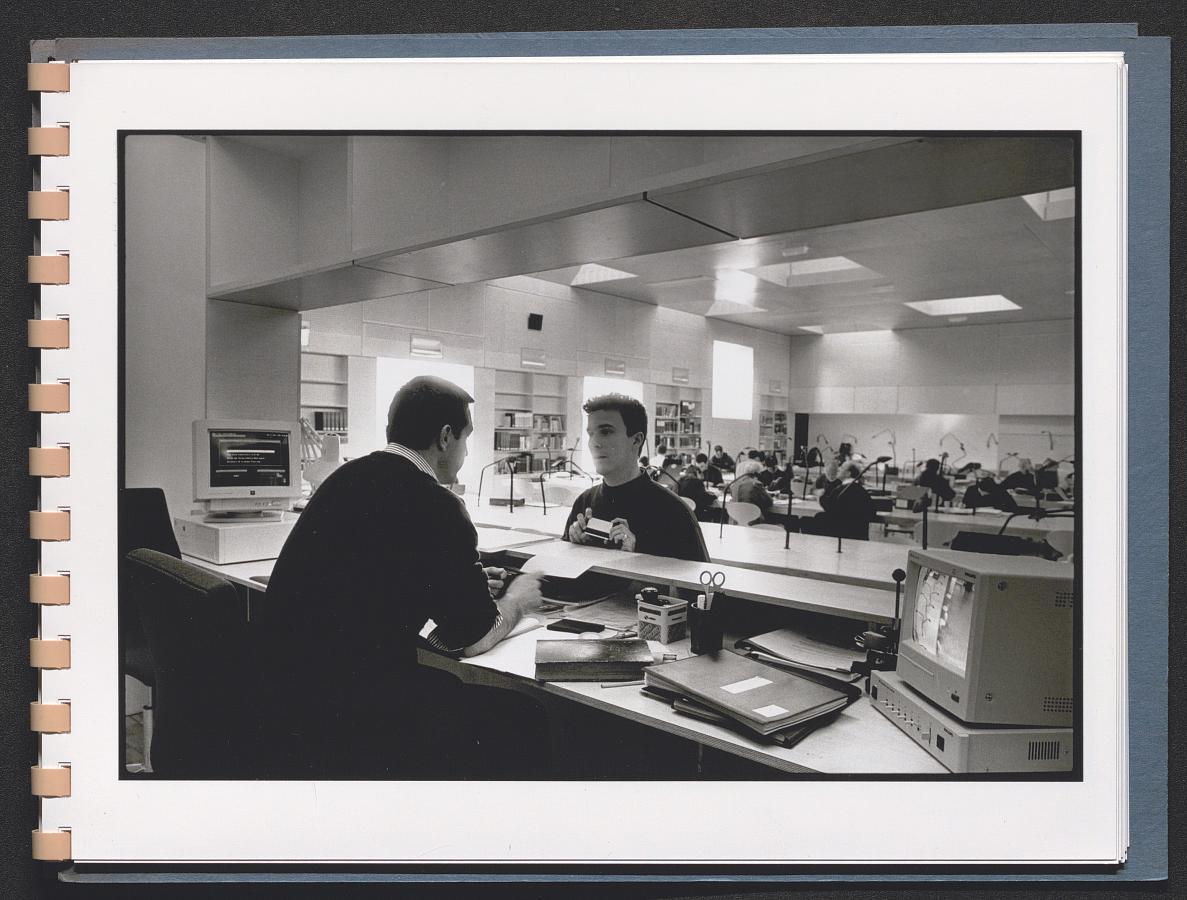 Photographie en noir et blanc représentant deux personnes, le président de salle et un lecteur, en salle de lecture