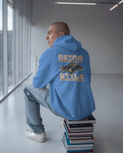 Modern Minimalist Hoodie Mockup Male Model In Blue Retro Style Design Sitting On Books Bright Glass Window Background