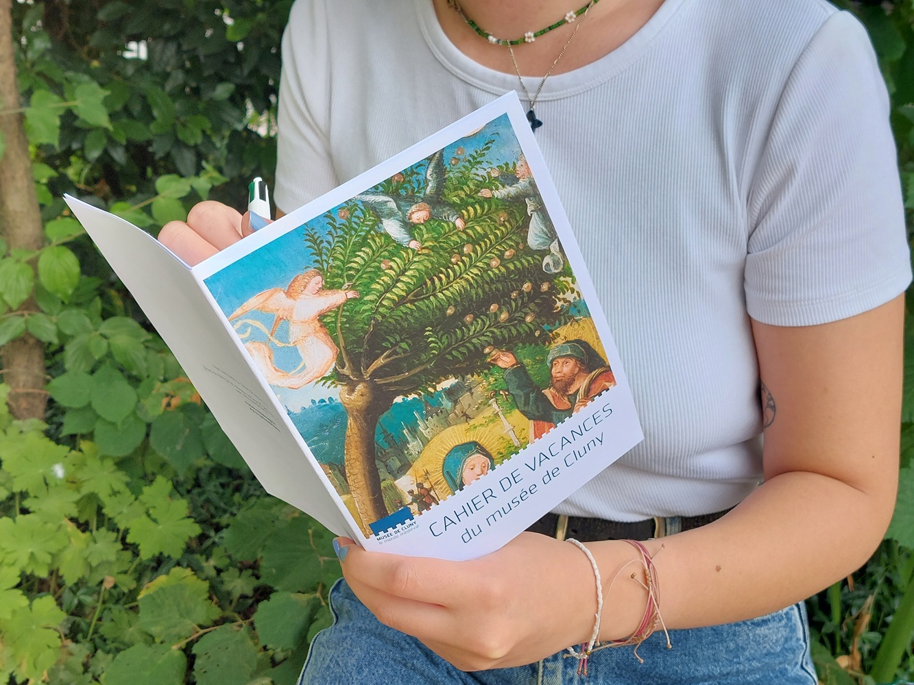 femme remplissant un cahier de vacances dans la nature