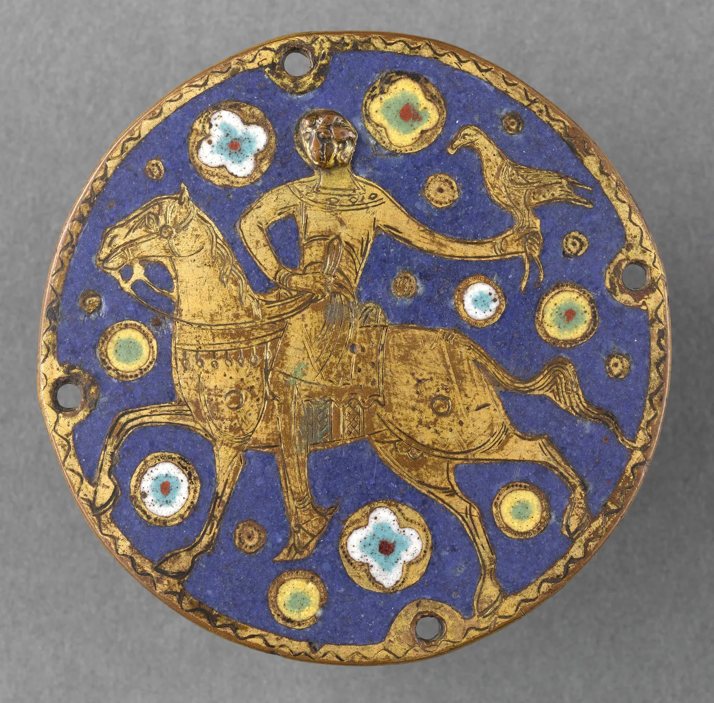 Médaillon gravé et émaillé orné d’un cavalier tenant un faucon sur fond d’émail bleu. Vue de face.