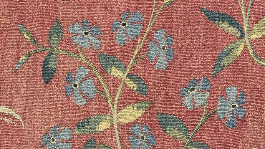 Tapisserie représentant des fleurs de pervenche bleues sur fond rouge. Vue de face.
