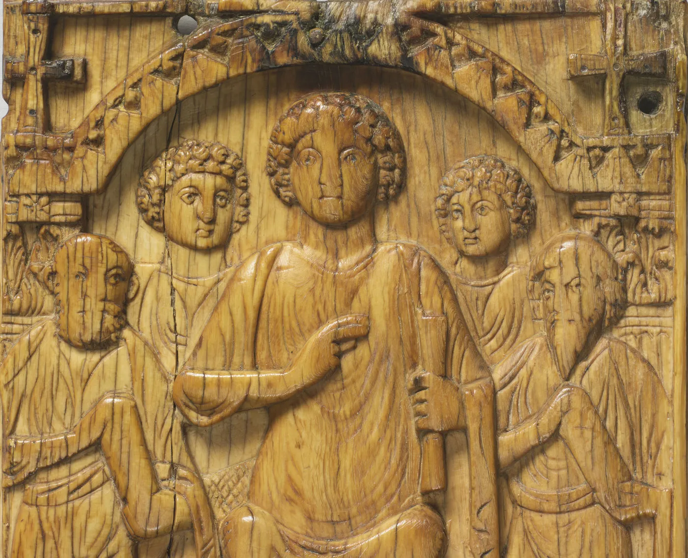 Détail d’une plaque d’ivoire sculpté : un homme entouré de personnages. Vue de face.