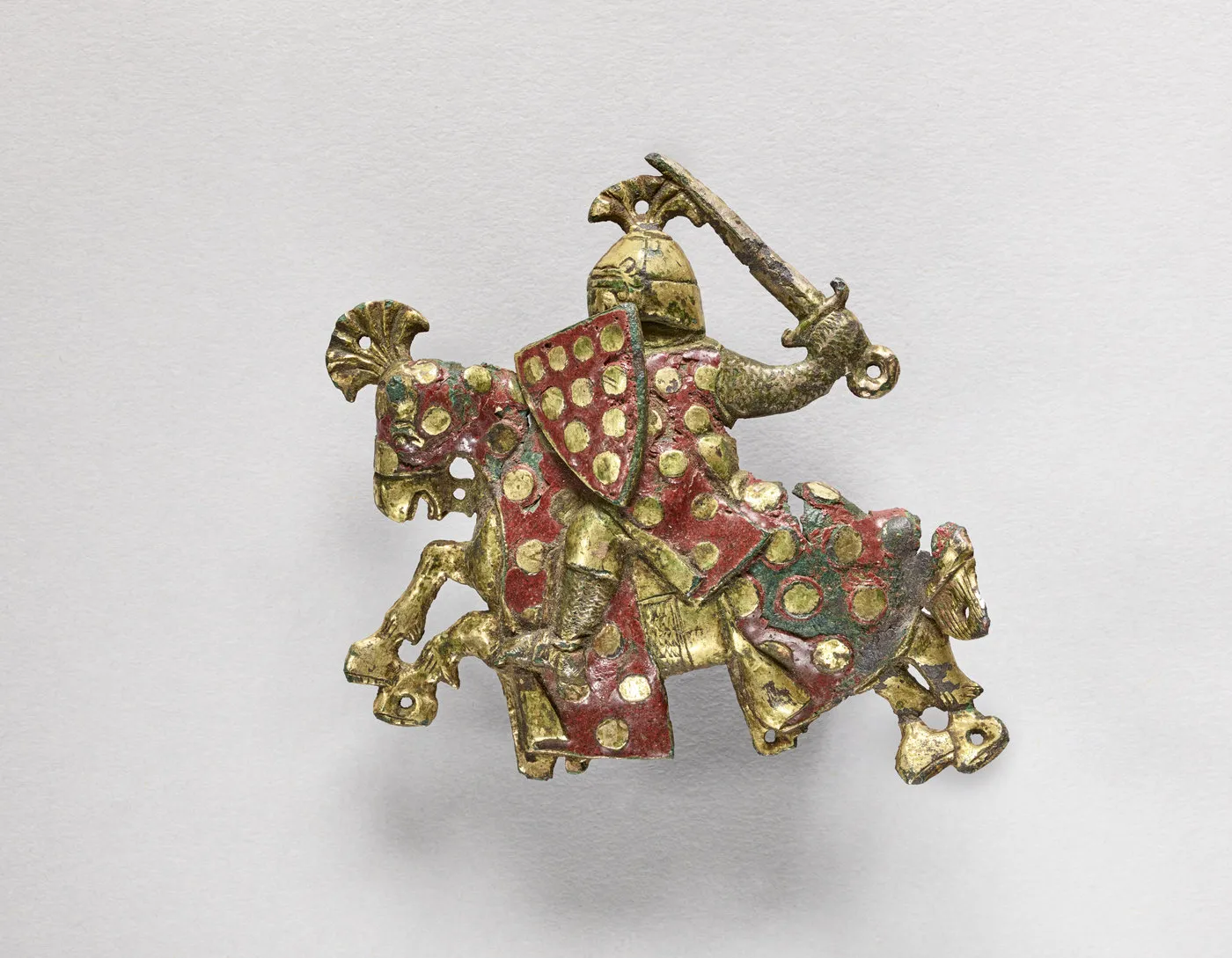 Objet métallique émaillé représentant un cavalier en armure de profil, brandissant son épée. Photographie de face.
