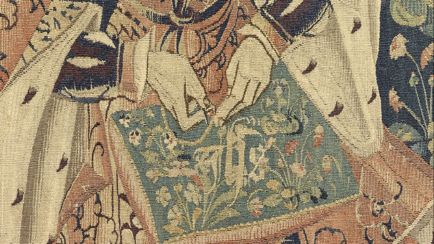 Détail d'une tapisserie centré sur l'ouvrage de broderie sur lequel une femme travaille. 