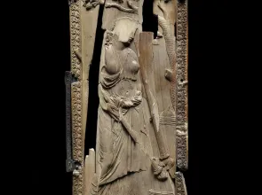 Plaque d’ivoire sculpté lacunaire représentant une femme de profil sous une branche de pin. Photographie de face.