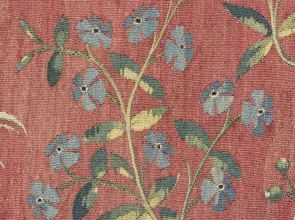 Tapisserie représentant des fleurs de pervenche bleues sur fond rouge. Vue de face.