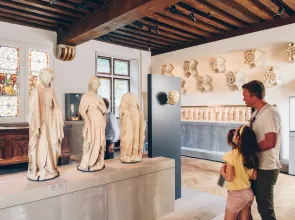 un homme et deux enfants devant des sculptures médiévales dans un musée