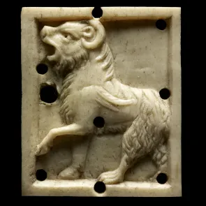Plaque d’ivoire sculpté représentant un lion cornu de profil. Photographie de face.