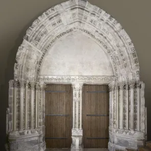 Carved stone portal adorned with columns and vegetal motifs. Front view.
