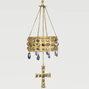 Gilded metal object with a hanging system, shaped like a crown with a suspended cross, adorned with cabochon stones. Front view.