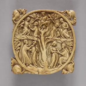 Medallón circular de marfil enmarcado por figuras animales fantásticas. El medallón está grabado con un árbol y personajes en sus ramas.