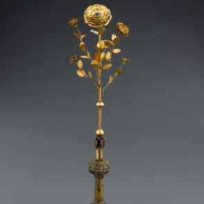 Gilded metal object: five rosebuds at different stages, with a central blooming rose adorned with a blue stone. Front view.