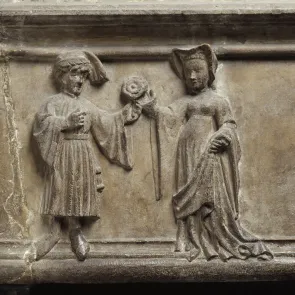 Sculpted stone element depicting a man offering a rose to a woman. Front view.