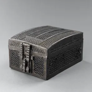 Coffret en bois recouvert de métal repercé en forme de mailles, présenté fermé. Vue de trois quarts.