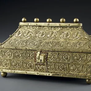 Metal casket adorned with lions and other chimerical animals. Three-quarter view.