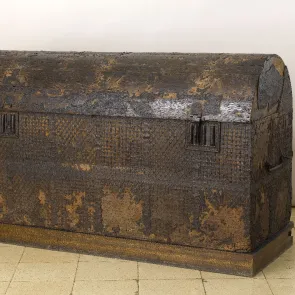Coffre de voyage en bois partiellement recouvert de cuir et à couvercle bombé. Vue de trois quarts.