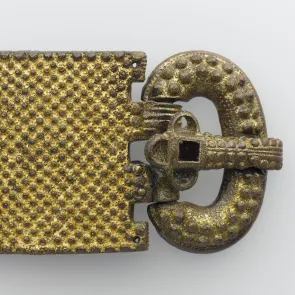 Objet métallique doré : plaque-boucle de ceinture ornée de points en relief. Vue de face.
