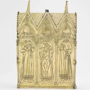 Objet en métal doré : bâtiment religieux gravé de personnages acéphales tenant leur tête, surmonté d’inscriptions. Vue de face.