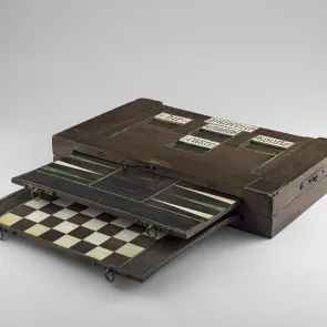 Boîte en bois avec un jeu de backgammon et de dames, compartiments pour pièces et dés en ivoire. Vue de trois quarts.