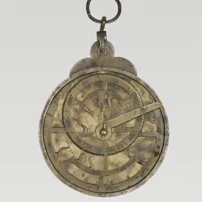 Metal object engraved with circles and inscriptions. Front view on a neutral background.