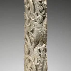 Sculpture en pierre représentant un homme de face dans un entrelac végétal. Vue de face.