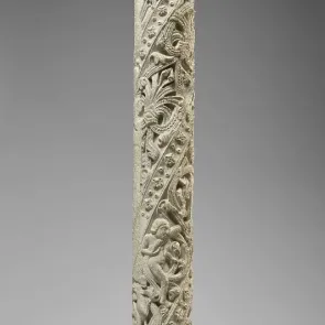Colonne en pierre sculptée ornée de motifs végétaux habités de personnages et d’animaux. Vue de face.