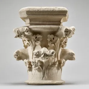 Capitel de piedra decorado con hojas de perejil plano. Fotografía frontal.