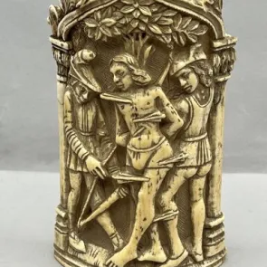 Carved ivory object depicting a man tied to a tree, pierced by arrows, and surrounded by two archers. Front view.