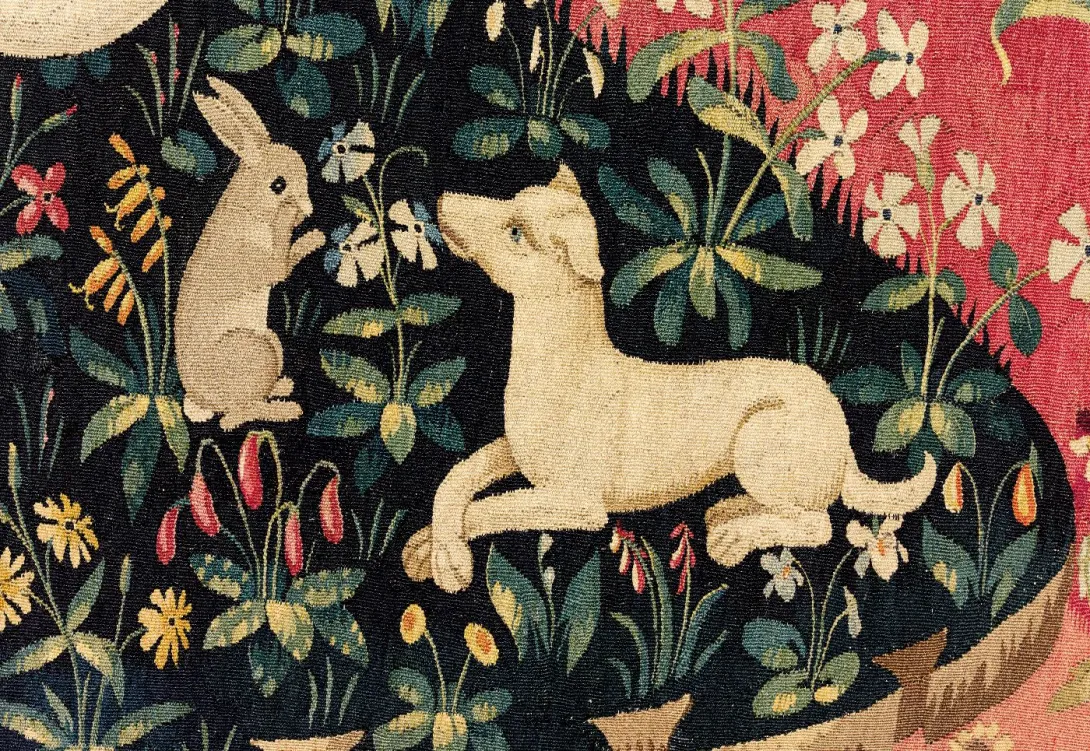 Tapisserie représentant un chien couché et un lapin se frottant le museau sur fond bleu parsemé de fleurs. Vue de face.