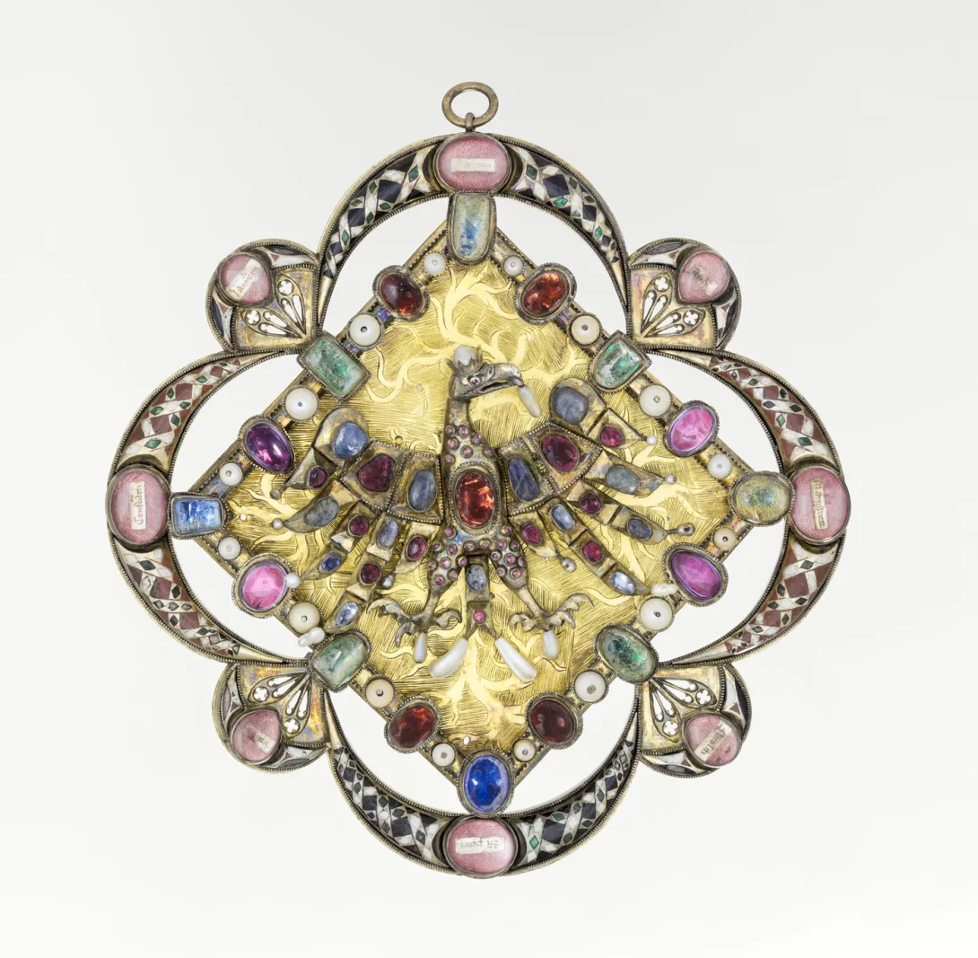 Objet métallique émaillé et ciselé orné d’un aigle incrusté de pierres et de perles. Vue de face.