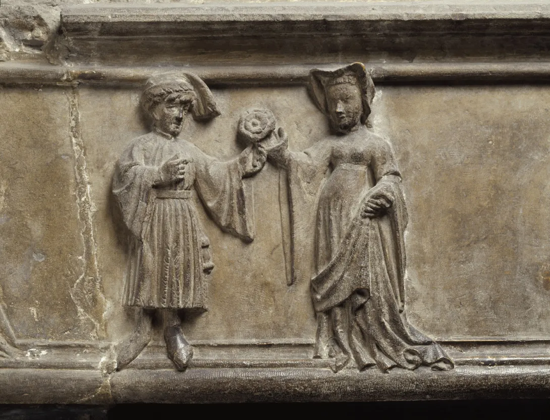Elemento de piedra esculpido que representa a un hombre ofreciendo una rosa a una mujer. Vista frontal.