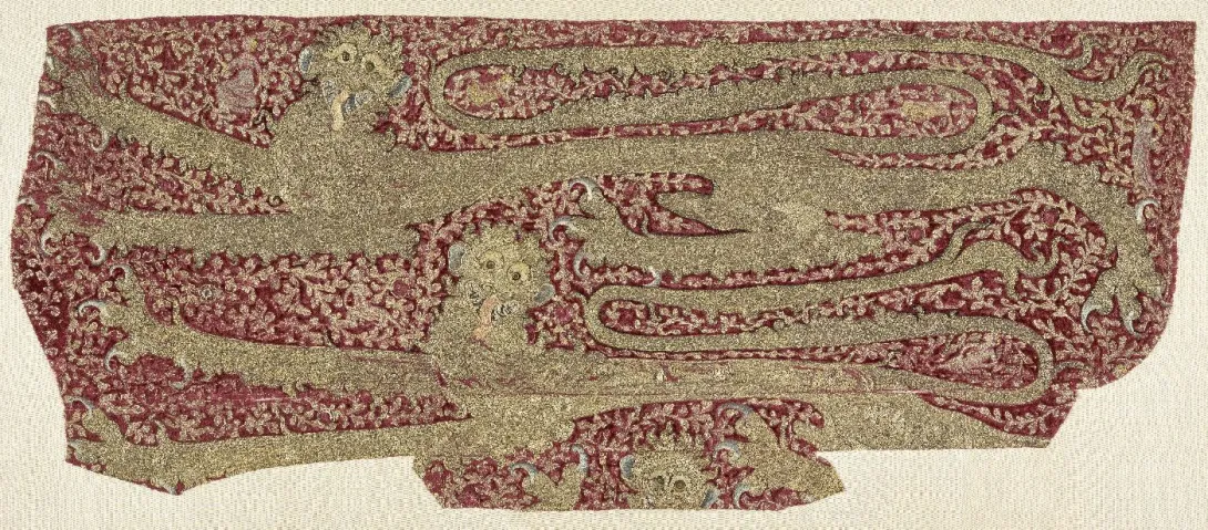 Broderie représentant deux léopards stylisés sur fond de feuillage animé de personnages. Photographie de face.