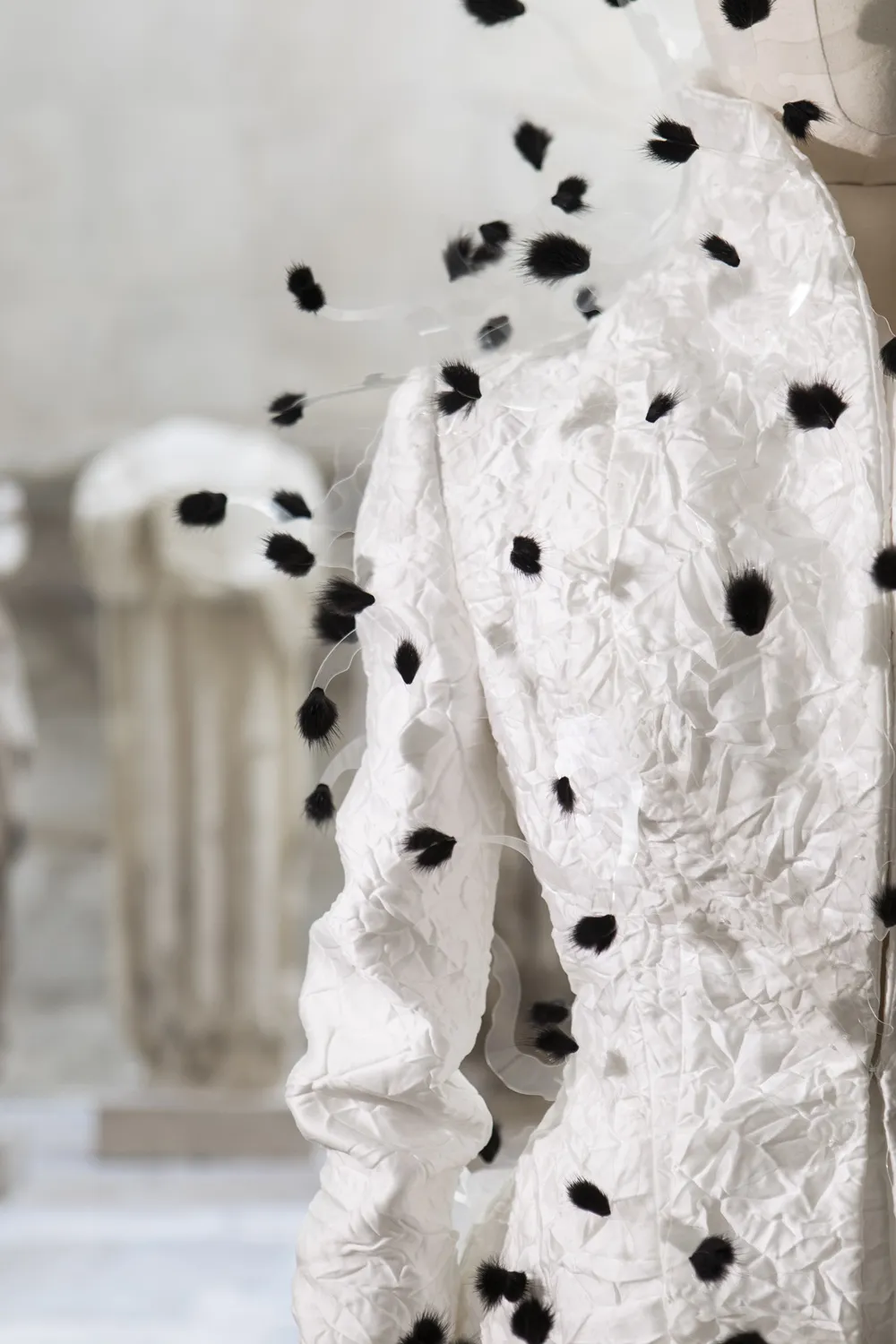 Détail d'une veste blanche avec tressage textile noir. Vue du col et d'une épaule.
