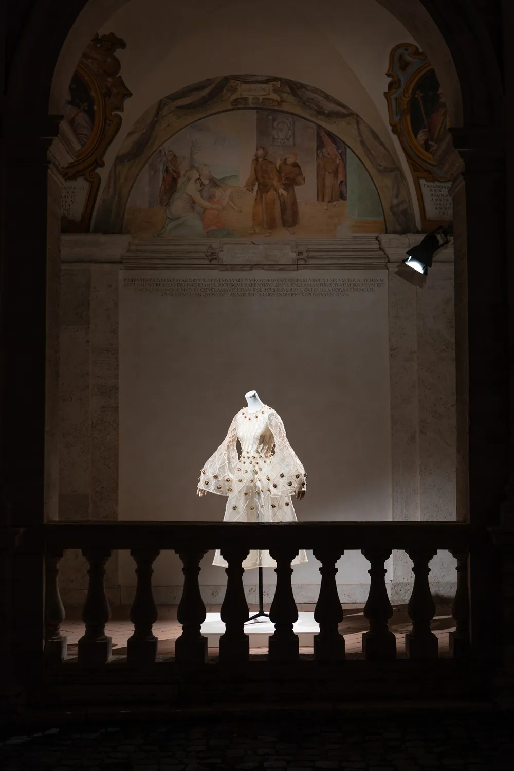 Robe éclairée dans la pénombre et placée sous une arche.