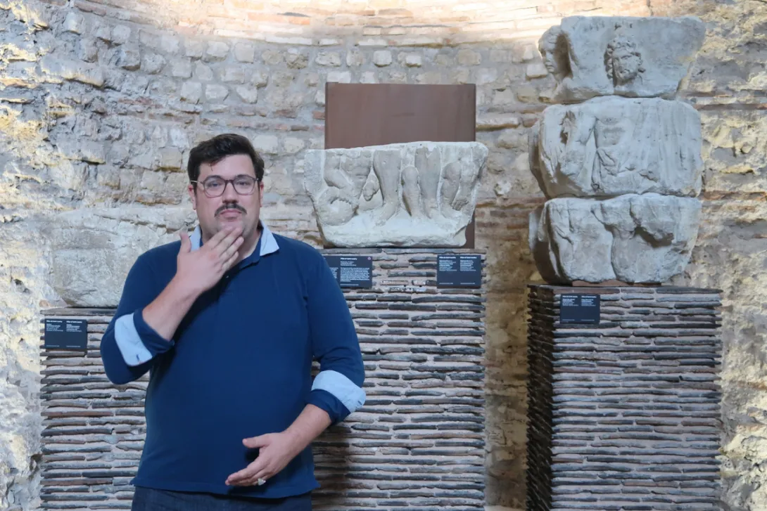 Un homme devant des sculptures antiques signe un mot en langue des signes française