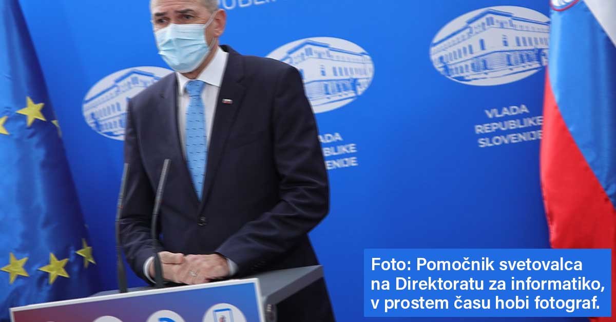 Fotografija Janeza Janše z novinarske konference, ki prikazuje res slabe fotografske spodobnosti osebe, ki je fotografijo naredila. Ob strani je napis Foto: Pomočnik svetovalca v direktoratu za informatiko, v prostem času hobi fotograf.