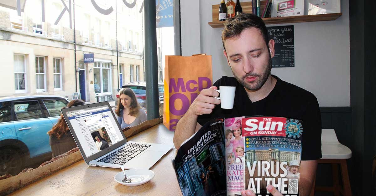 Moški sedi v kavarni, v desni drži skodelico kave, v levi pa trač revijo. Levo od njega je laptop z odprtim Facebookom, za njim vpa vrečka McDonald's hrane.