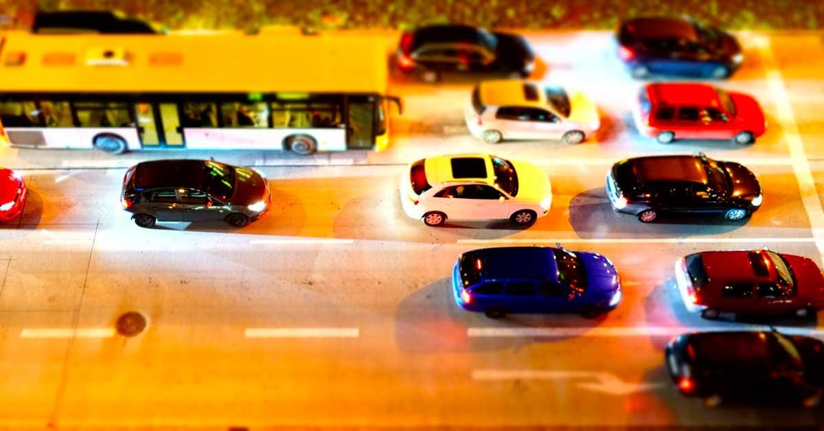 Cesta s pričje perspektive, na kateri stojijo avtobus in 11 avtomobilov.
