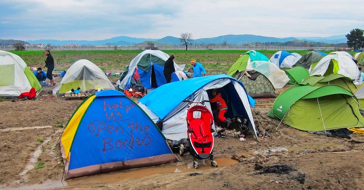 Begunski šotori na blatni zemlji, na enem je zapisano: